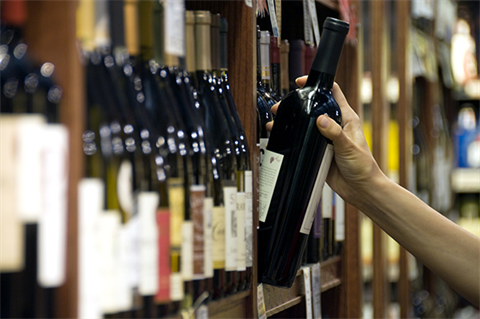 Alcohol Licensing - Fees & Charges - Hand reaching for a wine bottle off the shelf.